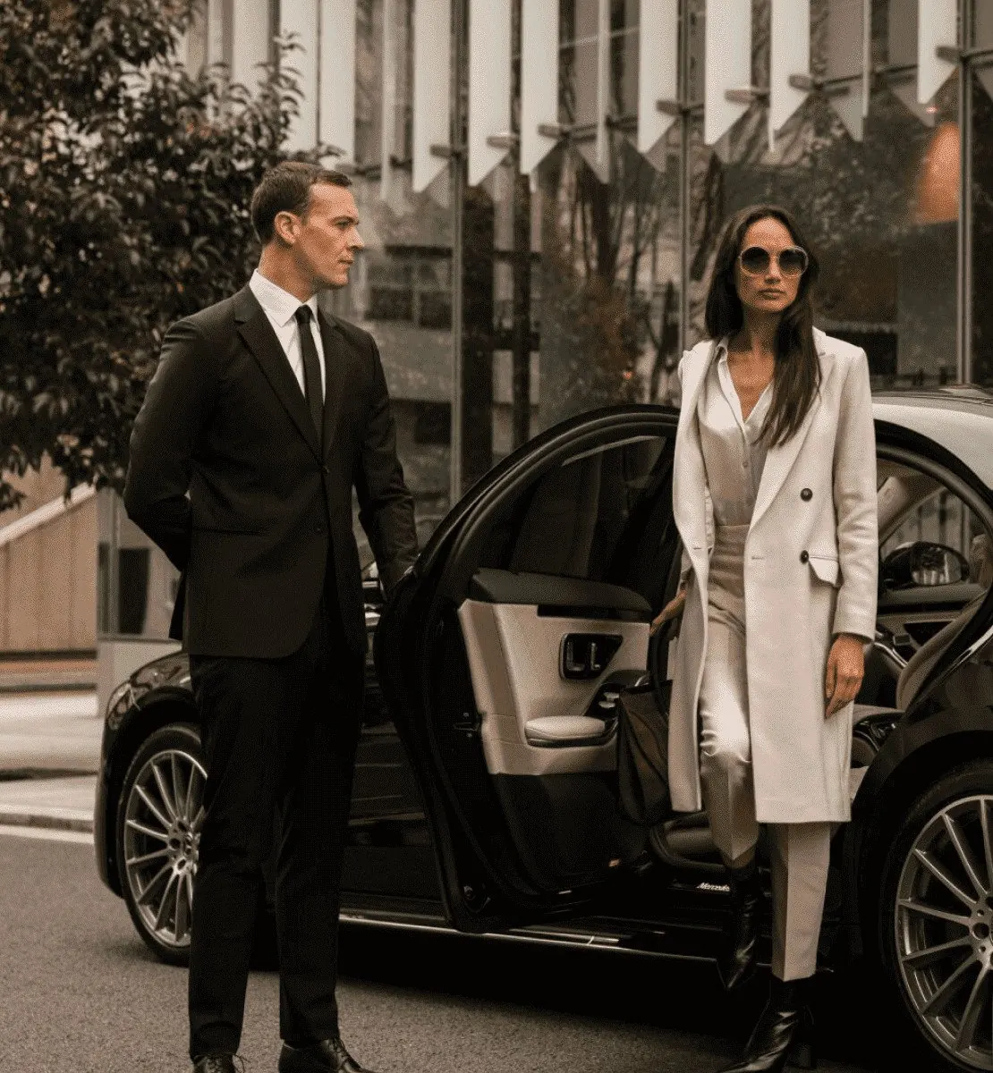 Chauffeur greeting a client beside a black luxury sedan in Dubai
