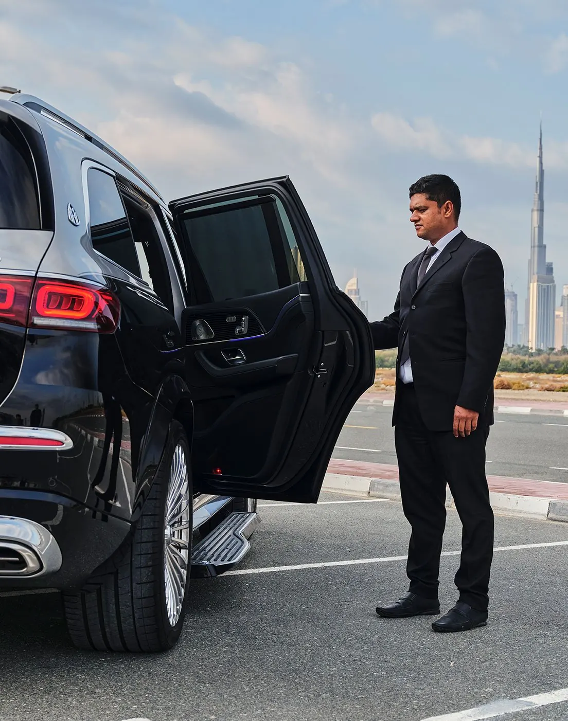 Chauffeur holding the door of a luxury SUV in Dubai