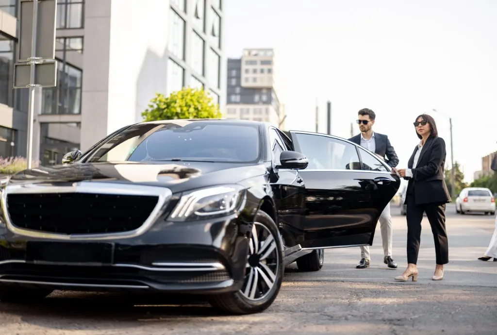 Business couple stepping into a Mercedes S-Class with chauffeur
